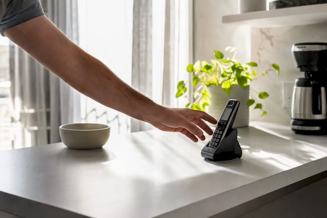 Hand holding home cordless phone in morning